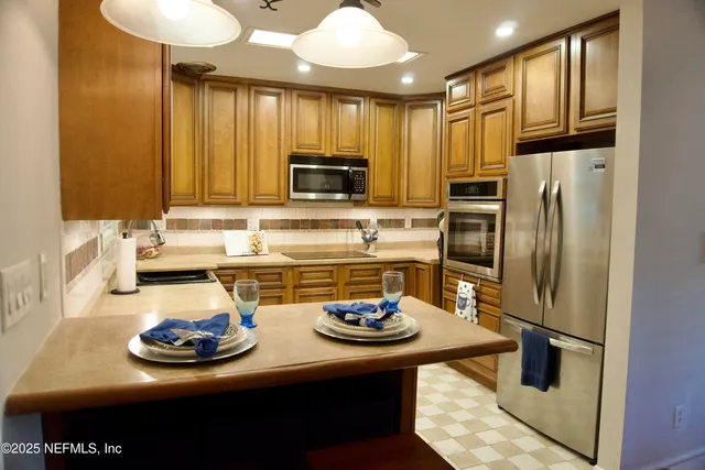 a kitchen with stainless steel appliances a sink a microwave a refrigerator and cabinets