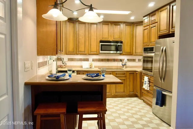 a kitchen with stainless steel appliances a sink a stove a refrigerator cabinets and a dining table
