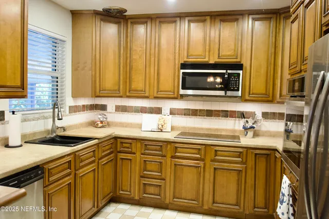 a kitchen with stainless steel appliances granite countertop a sink a stove a microwave cabinets and a window