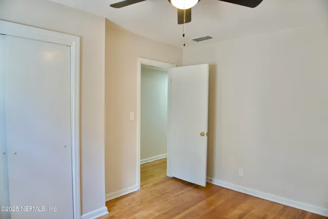 an empty room with wooden floor chandelier fan and closet
