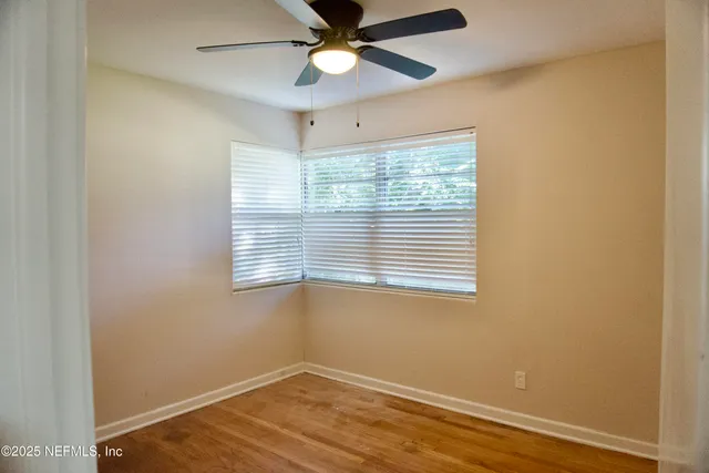 an empty room with a window and a fan
