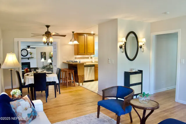 a living room with couches a fireplace and a dining table with wooden floor