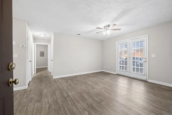 a view of an empty room with a window and wooden floor