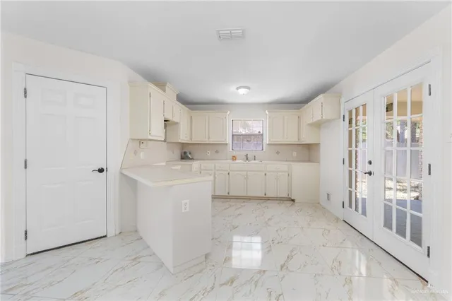 a view of a kitchen with white cabinets and wooden floor