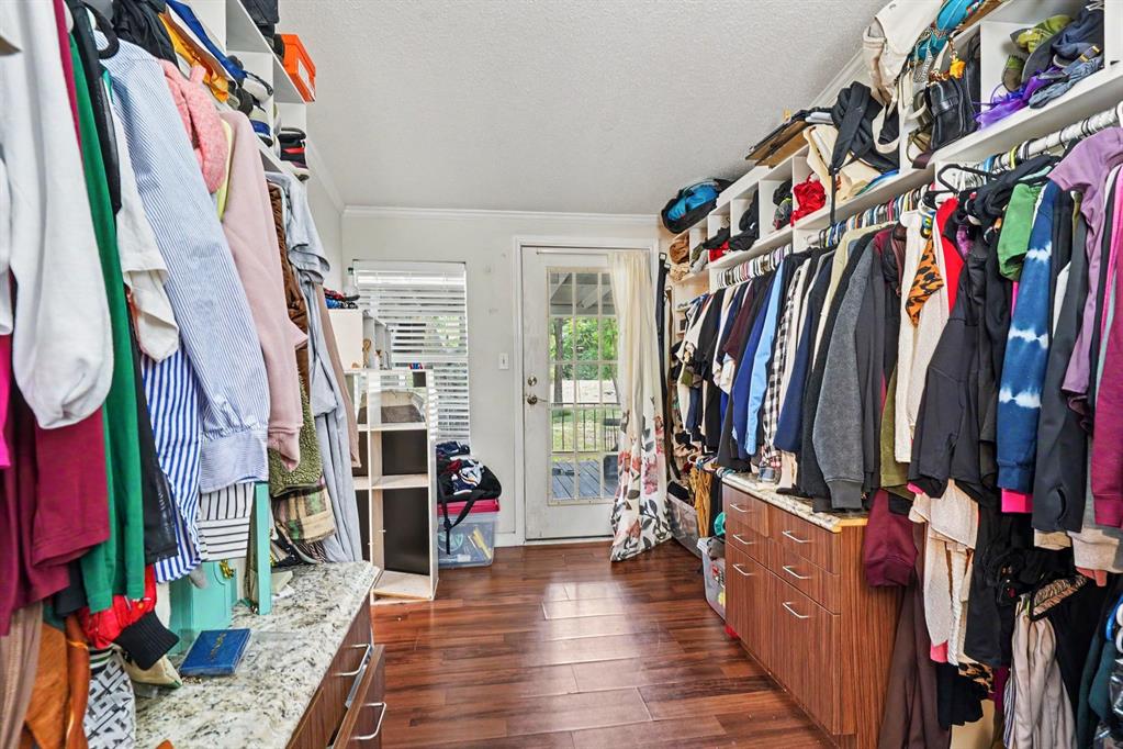 6356 Rendon Bloodworth Road Fort Worth, TX 76140 - Photo 23 of 25 Walk-in closet featuring wood-finish flooring, built-in shelving, integrated hanging rods, a French door, and a built-in dresser with a stone countertop