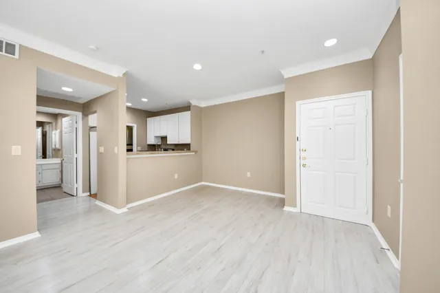a view of an empty room with window and wooden floor