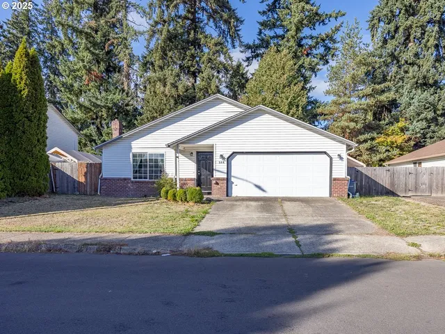 a view of a white house with a yard and large tree