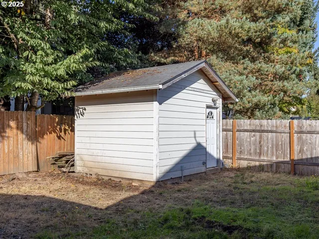 a view of a small house with a yard and large tree