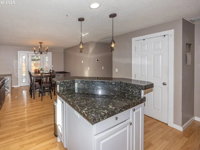 a kitchen with stainless steel appliances granite countertop a kitchen island a stove and a wooden floor