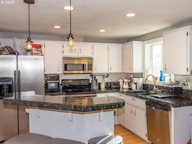 a kitchen with stainless steel appliances granite countertop a sink a stove and a refrigerator