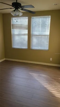 a view of empty room with wooden floor and fan