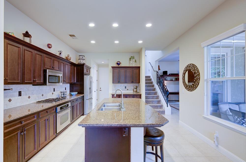 3852 Harlan Ranch Boulevard Clovis, CA 93619 - Photo 13 of 45 a kitchen with kitchen island granite countertop a stove top oven a sink a dining table and chairs