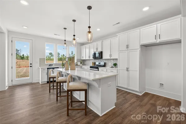 a kitchen with stainless steel appliances a dining table chairs stove and refrigerator