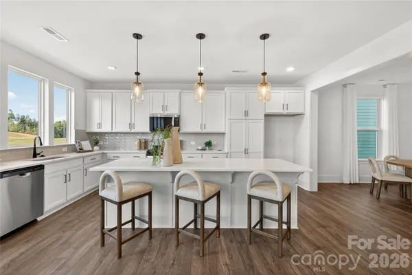 a kitchen with stainless steel appliances granite countertop a dining table chairs stove refrigerator and cabinets