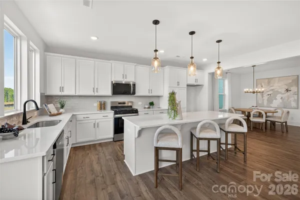 a large white kitchen with lots of counter space a sink appliances and cabinets
