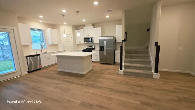 a view of kitchen with stainless steel appliances wooden floor and windows
