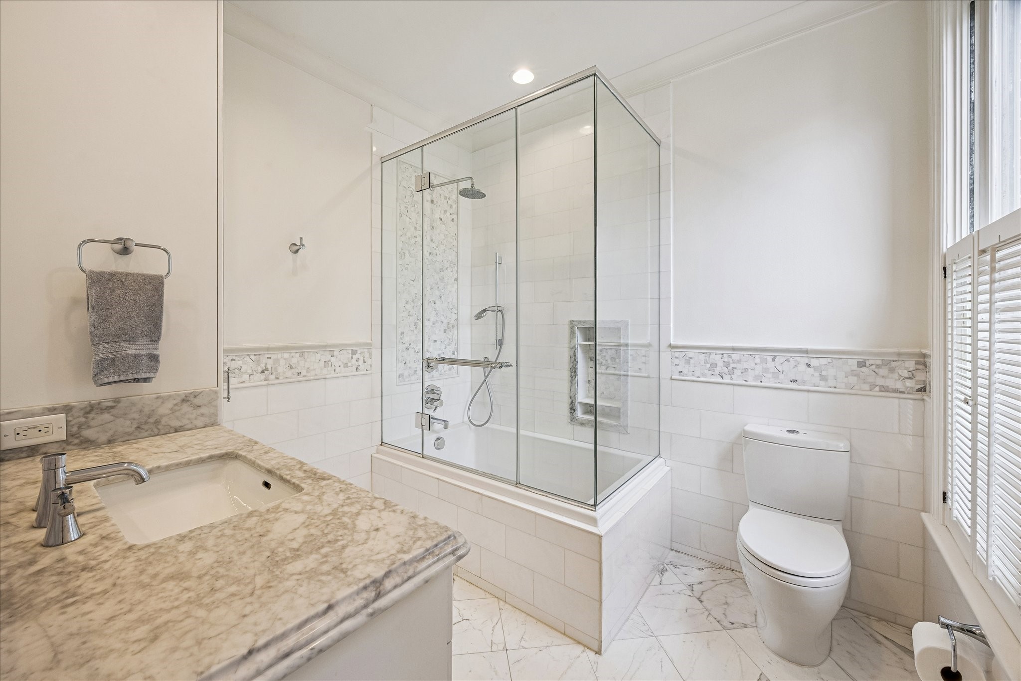 2368 Timber Lane Houston, TX 77027 - Photo 35 of 46 This beautifully appointed en suite bath is finished with elegant Calacatta marble flooring and countertops, creating a timeless and refined aesthetic. Designed with both comfort and functionality in mind, the space features a tub-shower with handheld sprayer, polished Hansgrohe Axor fixtures, a Toto undermount sink and commode, and custom cabinetry with integrated laundry storage.