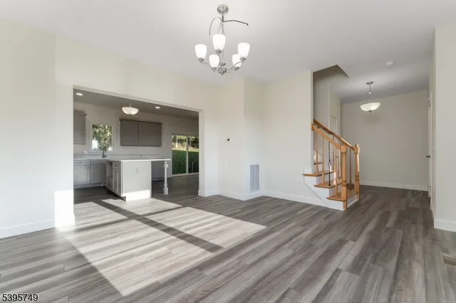 a view of a hallway with wooden floor and a kitchen space