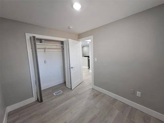 an empty room with wooden floor and entrance