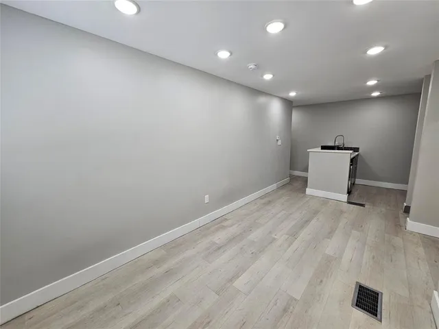 an empty room with wooden floor and a ceiling fan