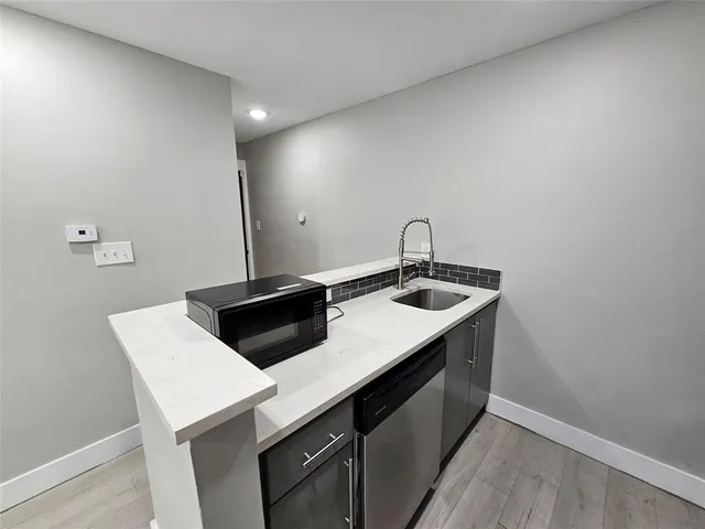 a kitchen with a sink dishwasher and a stove with wooden floor