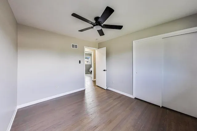 a view of empty room with wooden floor and ceiling fan
