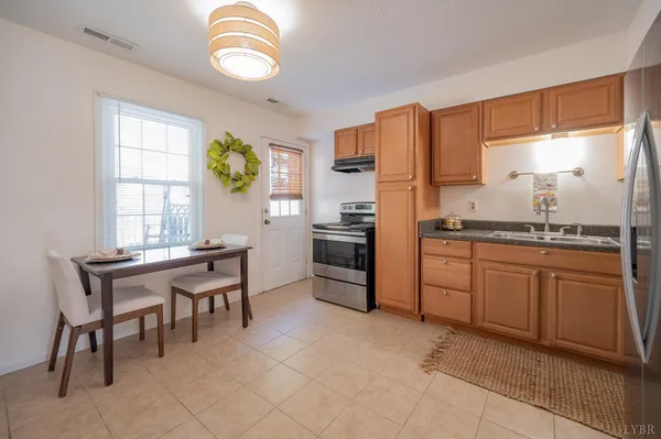 a kitchen with granite countertop stainless steel appliances a stove top oven a sink a dining table and chairs