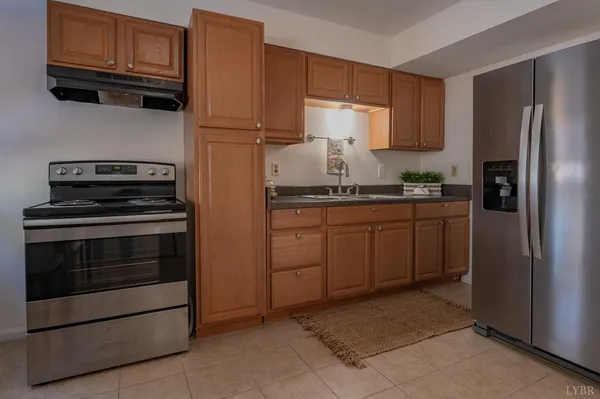 a kitchen with granite countertop a refrigerator stove and cabinets