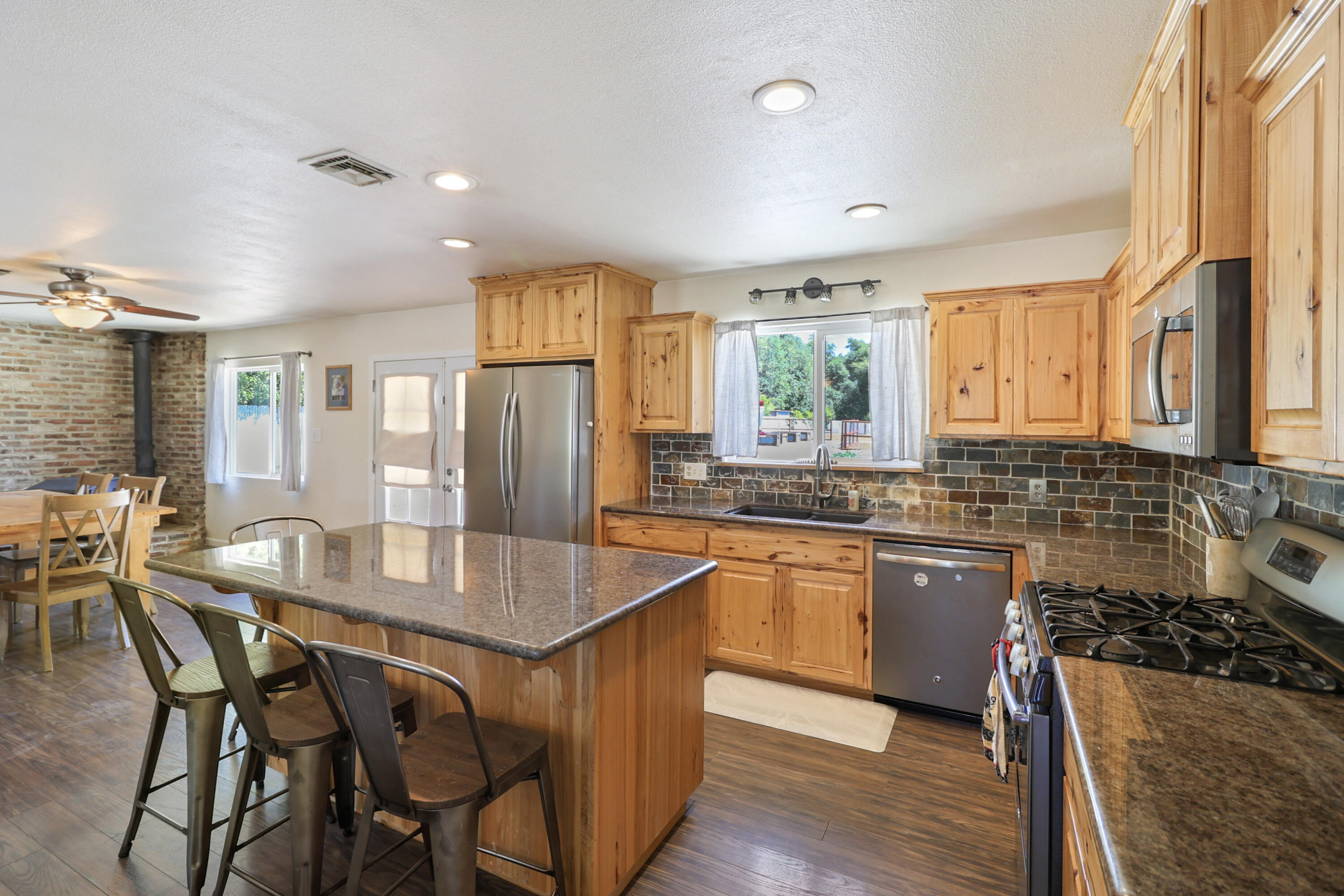 5201 Woodview Drive Redding, CA 96002 - Photo 11 of 57 a kitchen with stainless steel appliances granite countertop a stove a sink dishwasher a dining table and chairs with wooden floor