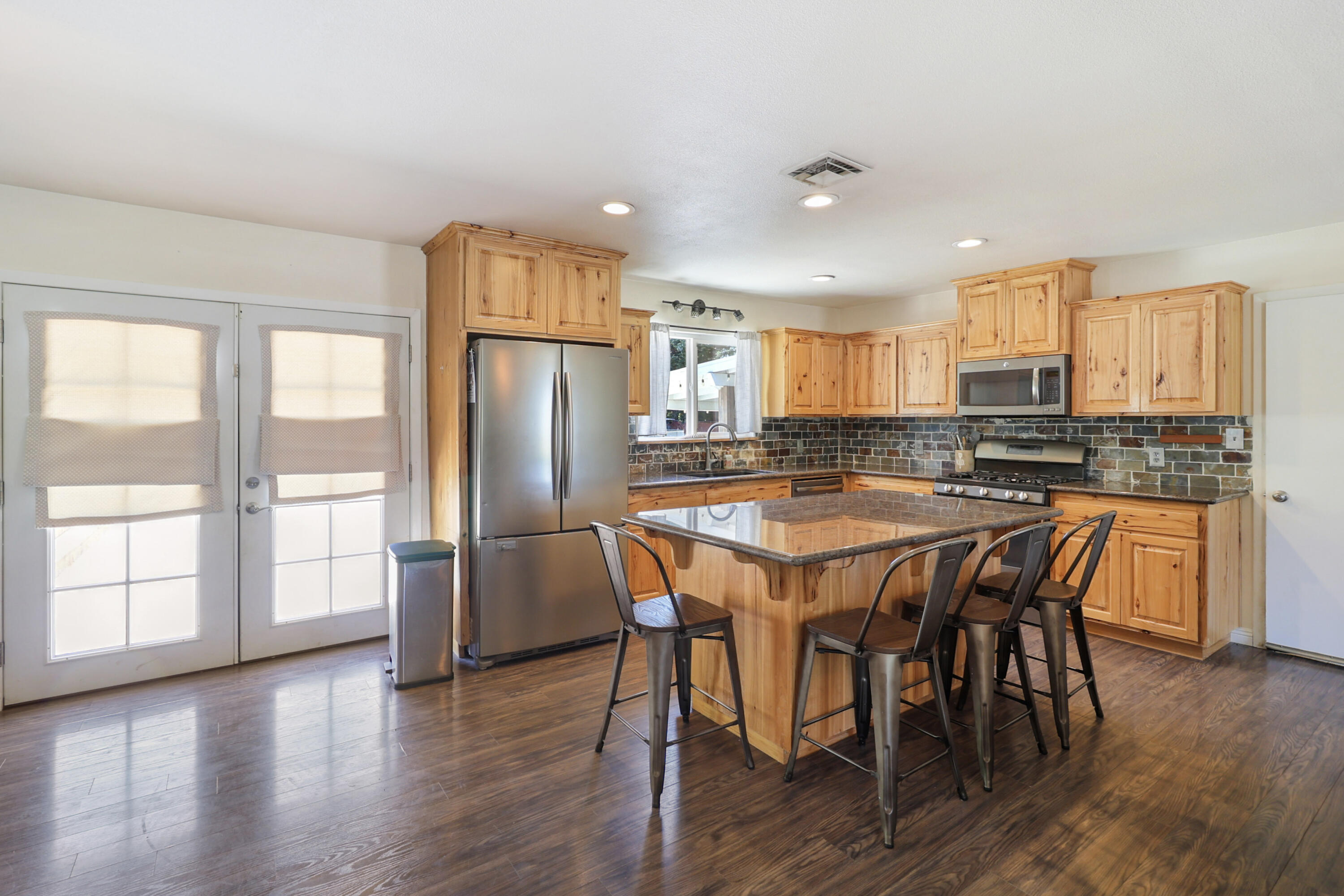 5201 Woodview Drive Redding, CA 96002 - Photo 10 of 57 a kitchen with stainless steel appliances granite countertop a stove a refrigerator a microwave a dining table and chairs with wooden floor