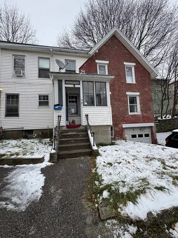 a front view of a house with a yard covered in snow