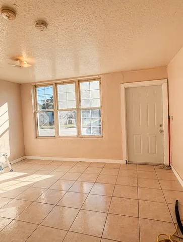 a view of an empty room with window and a kitchen