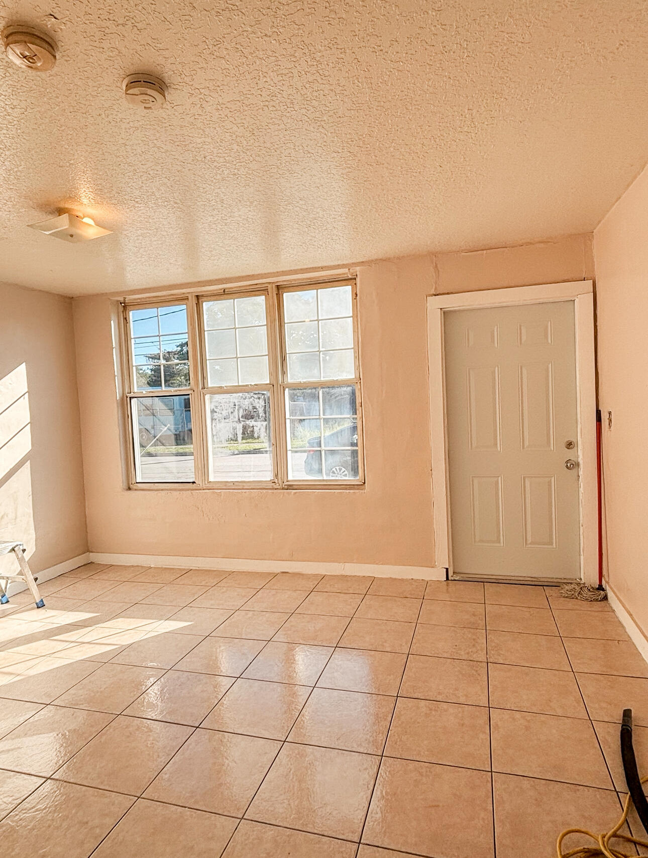 a view of an empty room with window and a kitchen