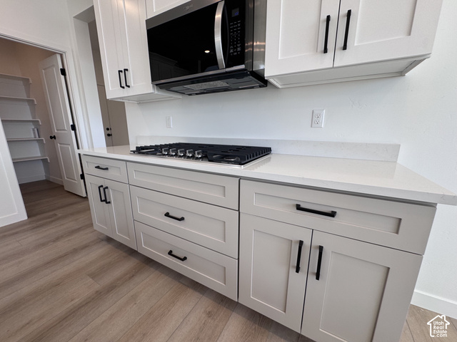 2633 Scarlet Road, Unit 259 Eagle Mountain, UT 84005 - Photo 7 of 29 White upper cabinetry with black hardware, integrated microwave, cooktop, and light-toned countertops