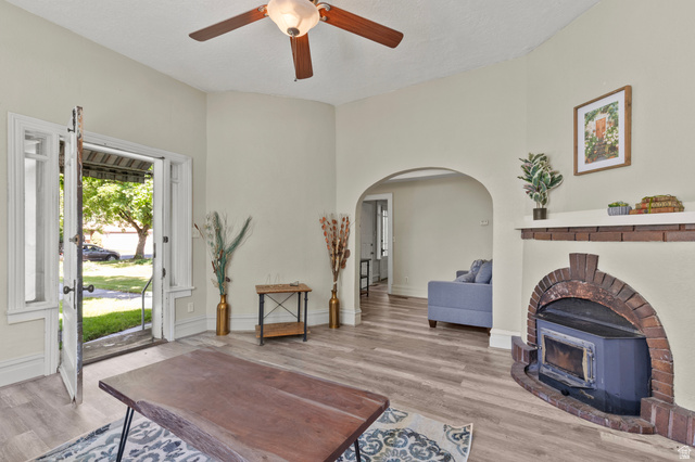 148 South 300 East Logan, UT 84321 - Photo 5 of 29 Living area featuring wood-finish flooring, a brick-surround fireplace with an insert, and an arched doorway