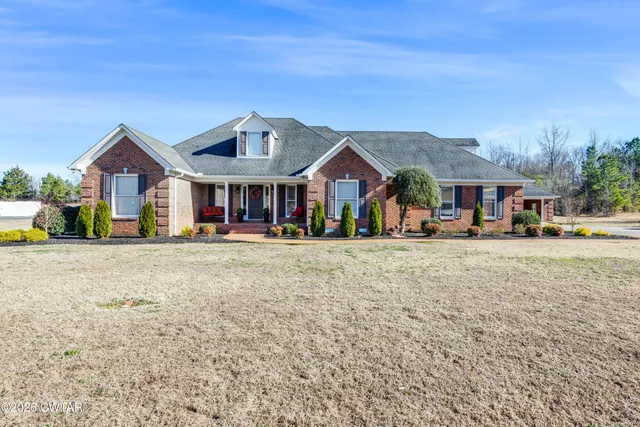 a view of a white house with a big yard and large trees