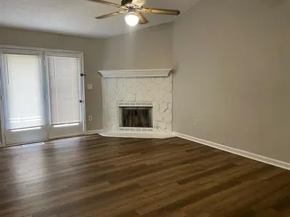 an empty room with wooden floor fireplace and windows
