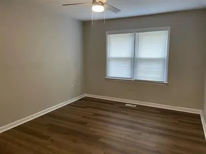an empty room with wooden floor and windows