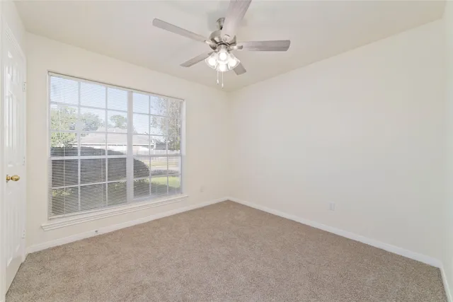 an empty room with a ceiling fan and window