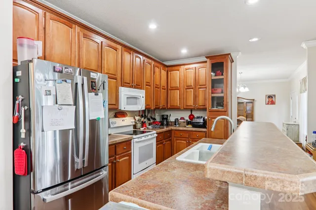 a kitchen with stainless steel appliances granite countertop a refrigerator a stove and a sink with wooden floor