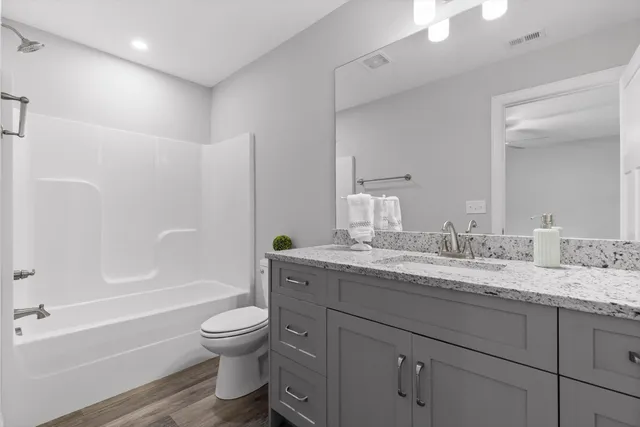 a bathroom with a granite countertop toilet a sink and a bathtub