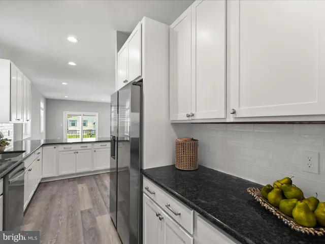 a kitchen with stainless steel appliances granite countertop a stove top oven a sink a refrigerator and white cabinets