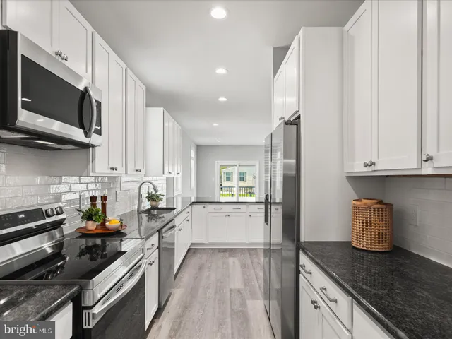 a kitchen with stainless steel appliances granite countertop a sink a stove and a refrigerator