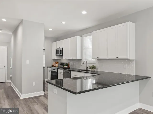 a kitchen with granite countertop a stove a sink and a window
