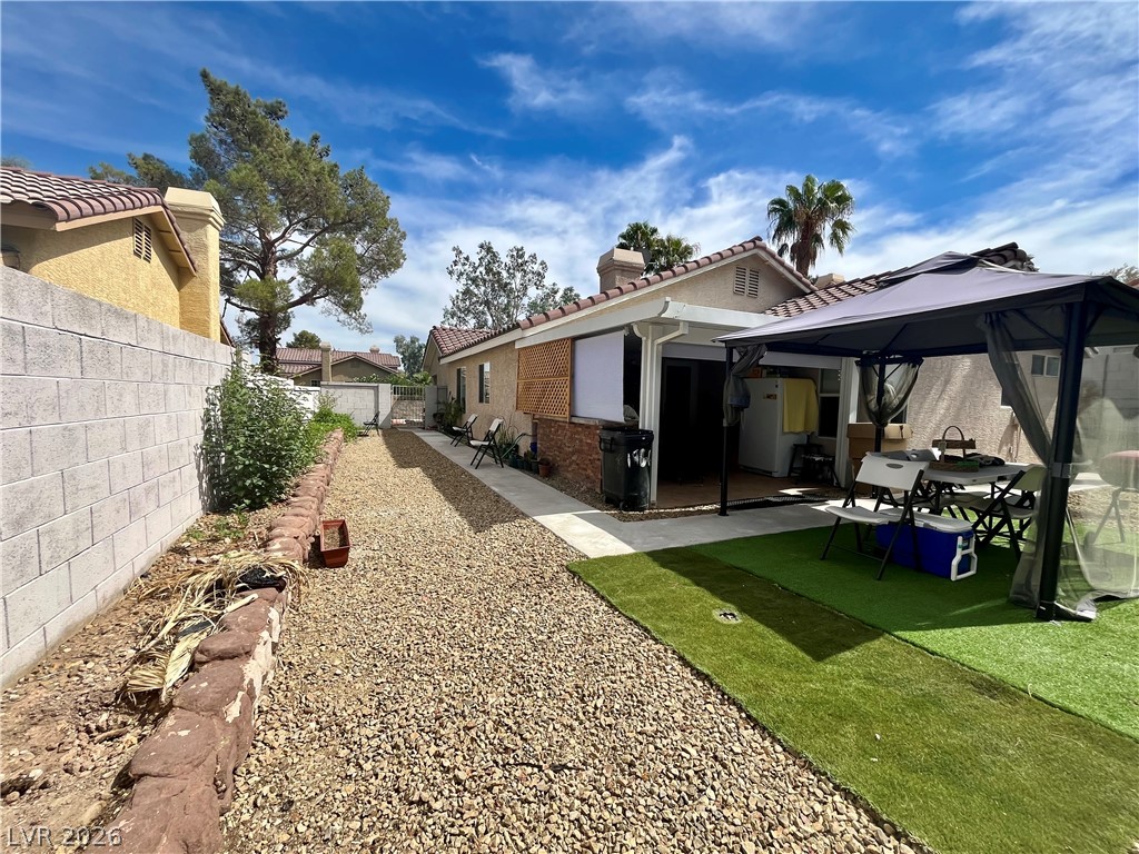 15 Rue Des Champs Henderson, NV 89074 - Photo 18 of 23 Low-maintenance landscaping and a stone block wall border the rear yard under sunny skies.