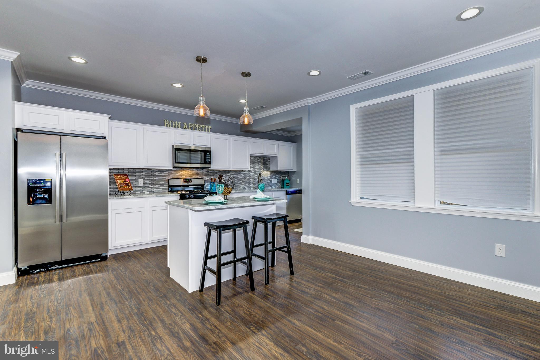 4622 Rokeby Road Baltimore, MD 21229 - Photo 7 of 27 a kitchen with stainless steel appliances granite countertop a refrigerator a stove top oven a sink dishwasher and white cabinets with wooden floor