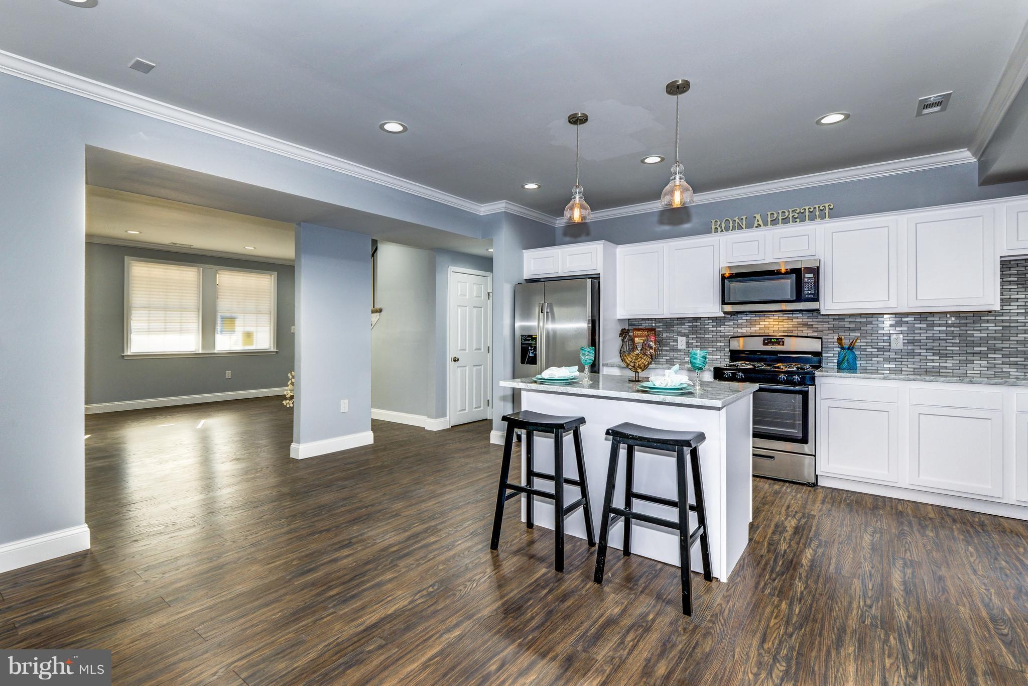4622 Rokeby Road Baltimore, MD 21229 - Photo 8 of 27 a kitchen with stainless steel appliances granite countertop a stove top oven a sink a dining table and chairs with wooden floor