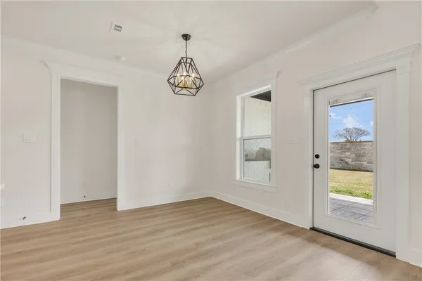 an empty room with wooden floor and chandelier