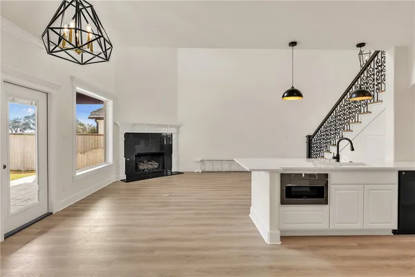a view of an empty room with wooden floor fireplace and a window