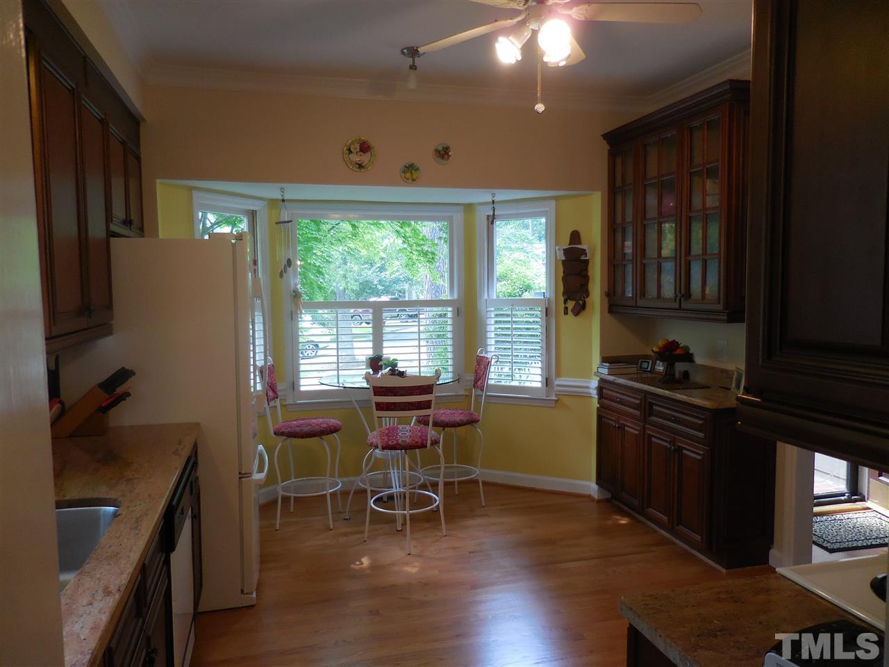 1307 Slatestone Court Raleigh, NC 27615 - Photo 6 of 25 a kitchen with granite countertop a stove a sink a dining table and chairs with wooden floor